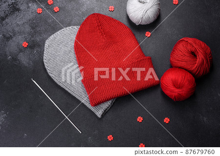 Red warm knitted women's hat on a concrete background 87679760