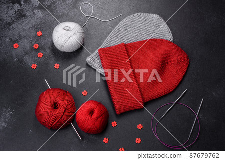 Red warm knitted women's hat on a concrete background Red warm knitted women's hat on a concrete background 87679762