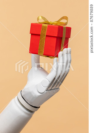 a bionic prosthetic arm or forearm in white on a beige background holds a red gift, prosthetics of limbs of arms and legs, modern cyber technologies 87679889