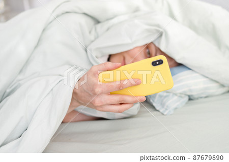 good morning, sunny day, caucasian woman checking messages, holding a yellow phone in her hand 87679890