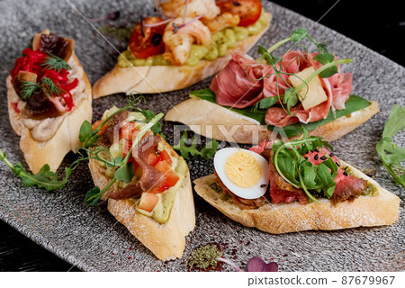 Oval brusquettes with different fillings on a gray oval plate Oval brusquettes with different fillings on a gray oval plate 87679967