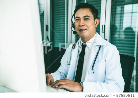 Doctor wearing headset talking actively on video call in a clinic or hospital . Doctor wearing headset talking actively on video call in a clinic or hospital . 87680611