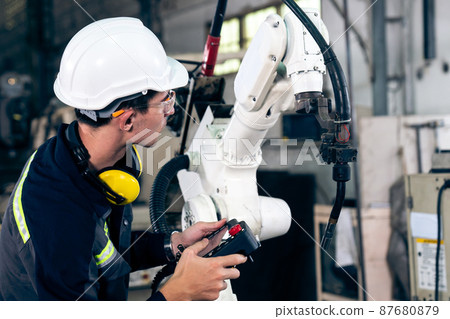Young factory worker working with adept robotic arm Young factory worker working with adept robotic arm 87680879