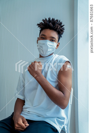 African American teenager showing COVID-19 vaccine bandage merrily African American teenager showing COVID-19 vaccine bandage merrily 87681663