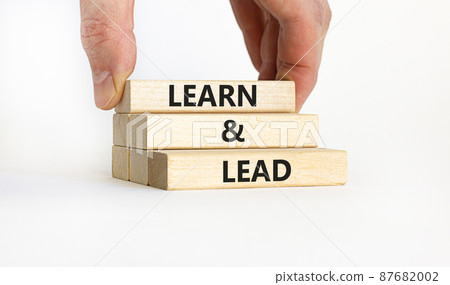 Learn and lead symbol. Concept words 'Learn and lead'. Businessman hand. Beautiful white background. Business, educational and learn and lead concept, copy space. Learn and lead symbol. Concept words 'Learn and lead'. Businessman hand. Beautiful white background. Business, educational and learn and lead concept, copy space. 87682002