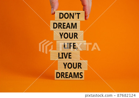 Live your dreams symbol. Wooden blocks with words Do not dream your life, live your dreams. Beautiful orange background. Businessman hand. Business and live your dreams concept. Copy space. Live your dreams symbol. Wooden blocks with words Do not dream your life, live your dreams. Beautiful orange background. Businessman hand. Business and live your dreams concept. Copy space. 87682124