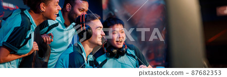 Happy gamers involved in online video game at computer club 87682353