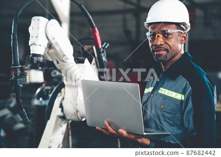 African American factory worker working with adept robotic arm African American factory worker working with adept robotic arm 87682442