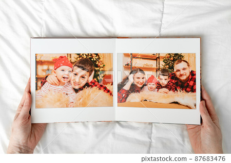 a hands with a book with photos of big family on a white background. a hands with a book with photos of big family on a white background. 87683476