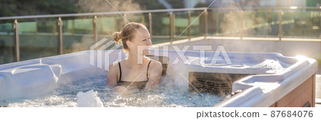 BANNER, LONG FORMAT Portrait of young carefree happy smiling woman relaxing at hot tub during enjoying happy traveling moment vacation life against the background of green big mountains BANNER, LONG FORMAT Portrait of young carefree happy smiling woman relaxing at hot tub during enjoying happy traveling moment vacation life against the background of green big mountains 87684076