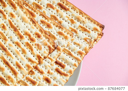 Happy Passover. Matzo on a pink background. Traditional Jewish food for regilious spring holiday of Pesach. Happy Passover. Matzo on a pink background. Traditional Jewish food for regilious spring holiday of Pesach. 87684077