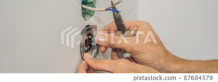 Master electrician installs a socket in the house BANNER, LONG FORMAT 87684379