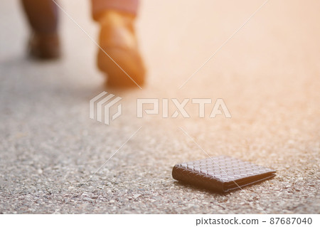 businessman had lost leather wallet with money on the street. Close-up of wallet lying on the sidewalk in during the trip to work. 87687040