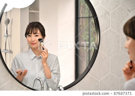 一個女人在鏡子前化妝 87687371