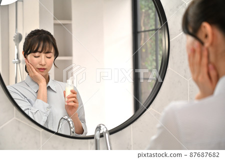 A woman putting on makeup in front of a mirror 87687682