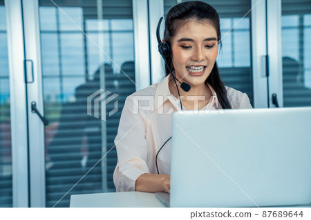 Businesswoman wearing headset working actively in office Businesswoman wearing headset working actively in office 87689644