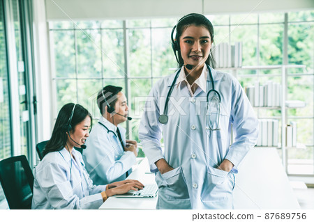 Doctor team wearing headset talking actively on video call in hospital clinic Doctor team wearing headset talking actively on video call in hospital clinic 87689756