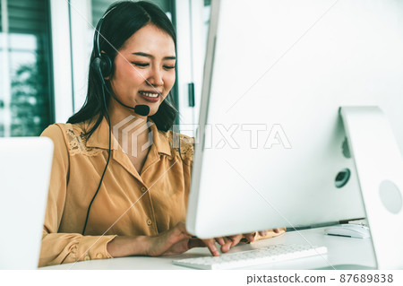 Businesswoman wearing headset working actively in office Businesswoman wearing headset working actively in office 87689838