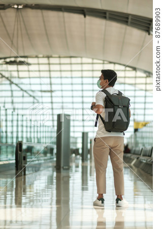 Young male wearing face mask with bagckpack walking in airport, protection Coronavirus disease infection, Asian man traveler. Time to travel after vaccine booster dose concept Young male wearing face mask with bagckpack walking in airport, protection Coronavirus disease infection, Asian man traveler. Time to travel after vaccine booster dose concept 87689903