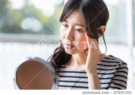 Middle-aged woman suffering from skin problems in front of the mirror 87691302
