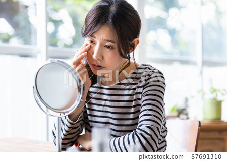 Middle-aged woman suffering from skin problems in front of the mirror 87691310