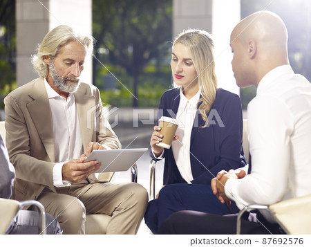 multiethnic coporate people meeting discussing business using digital tablet in modern building 87692576