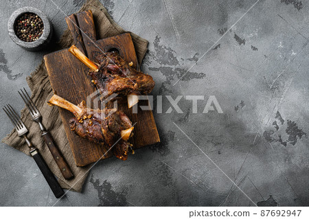 Baked lamb shank with barley and ale, on gray stone table background, top view flat lay, with copy space for text Baked lamb shank with barley and ale, on gray stone table background, top view flat lay, with copy space for text 87692947