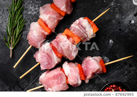 Raw shish kebab. Barbecue Meat Spices and Herbs, top view flat lay, on black dark stone table background Raw shish kebab. Barbecue Meat Spices and Herbs, top view flat lay, on black dark stone table background 87692993