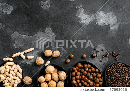 A variety of nuts, peanut, walnut, pine nuts and hazelnut, on black dark stone table background, top view flat lay, with copy space for text A variety of nuts, peanut, walnut, pine nuts and hazelnut, on black dark stone table background, top view flat lay, with copy space for text 87693016