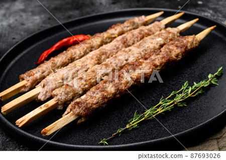 Minced and shaped lamb mutton kebabs, on plate, on black dark stone table background 87693026