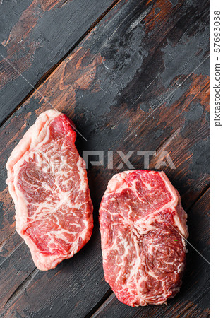 Top blade organic meat cut, raw marbled beef steak, On dark wooden background, top view with space for text. Top blade organic meat cut, raw marbled beef steak, On dark wooden background, top view with space for text. 87693038