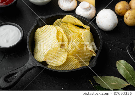 Home made potato chips, on black stone background Home made potato chips, on black stone background 87693336