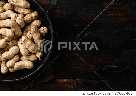 Peanuts serving to make oil, peanut butter, on old dark wooden table background, top view flat lay, with copy space for text 87693402
