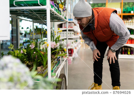 a man in the garden center chooses flowers for his beloved woman 87694026