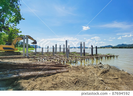 The construction of a small jetty for the convenience of boarding and landing jet skis along the river. Build a berth that juts out into the river with beams made of logs and cement columns. 87694592
