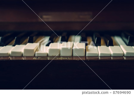 Close up shot to broken piano keys in abandoned house. An ancient musical instrument. Old broken disused piano with damaged keys Vintage Retro Filter. Distressed Piano made of wood. Selective Focus. Close up shot to broken piano keys in abandoned house. An ancient musical instrument. Old broken disused piano with damaged keys Vintage Retro Filter. Distressed Piano made of wood. Selective Focus. 87694690