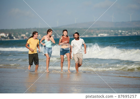 Happy Couples Jogging on Beach 87695257