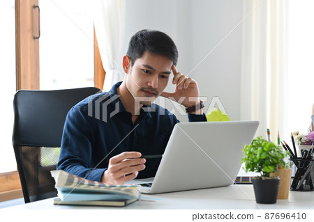 Thoughtful asian man designer working with computer laptop at creative office. 87696410