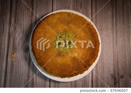 Delicious Traditional Dessert Knafeh with cheese and pistachios and orange flower syrup Delicious Traditional Dessert Knafeh with cheese and pistachios and orange flower syrup 87696807