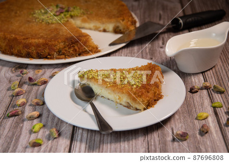 Delicious Traditional Dessert Knafeh with cheese and pistachios and orange flower syrup Delicious Traditional Dessert Knafeh with cheese and pistachios and orange flower syrup 87696808