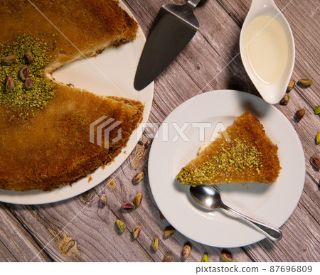 Delicious Traditional Dessert Knafeh with cheese and pistachios and orange flower syrup Delicious Traditional Dessert Knafeh with cheese and pistachios and orange flower syrup 87696809