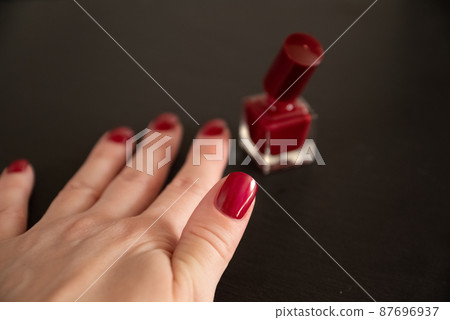 Woman hand with red nail polish on fingernails. Beauty treatment and hand care, manicure procedure 87696937