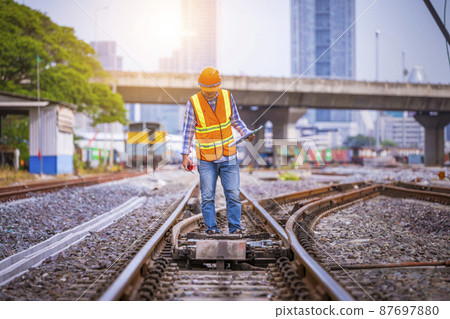 Engineer railway under checking construction process train testing and checking railway work on railroad station with radio communication .Engineer wearing safety uniform and safety helmet in work. Engineer railway under checking construction process train testing and checking railway work on railroad station with radio communication .Engineer wearing safety uniform and safety helmet in work. 87697880