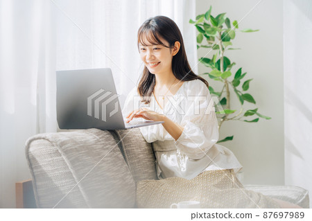 Woman using a computer on the sofa Woman using a computer on the sofa 87697989