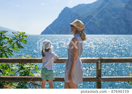 Mother and daughter admire the scenery of the Alps and Lake Garda at Italy 87698159