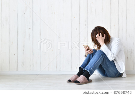 A woman scratching her head looking at her smartphone 87698743