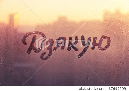 Ukrainian language word thanks in english are painted on wet orange sunrise glass of window 87699309