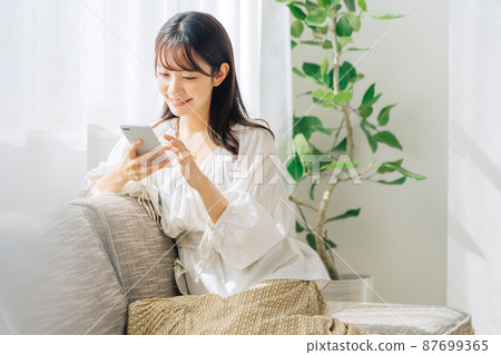 坐沙發和看智能手機的婦女 坐沙發和看智能手機的婦女 87699365