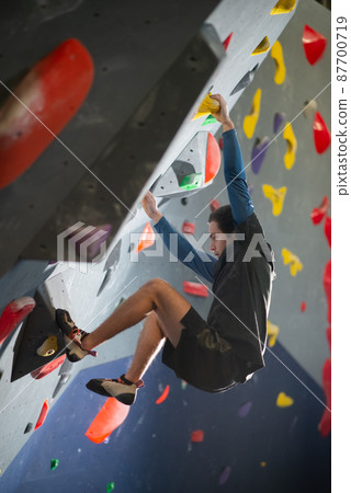 Young athlete doing bouldering 87700719