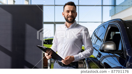 representative of a car dealership with a tablet in his hands against the background of a new car representative of a car dealership with a tablet in his hands against the background of a new car 87701176
